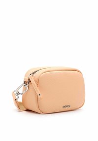 Koženková crossbody taška v broskvové barvě, zaobleného tvaru, se zipovým uzavřením a kovovými detaily. Obsahuje odnímatelný popruh a texturovaný povrch.