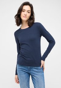 Marineblaue Langarm-T-Shirt aus weichem Stoff, mit Rundhalsausschnitt und körpernaher Passform, kombiniert mit hellblauen Jeans.