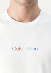 Witte katoenen t-shirt met een centraal geplaatste, multicolore "Calvin Klein"-logo. Klassiek crew neck ontwerp met korte mouwen.