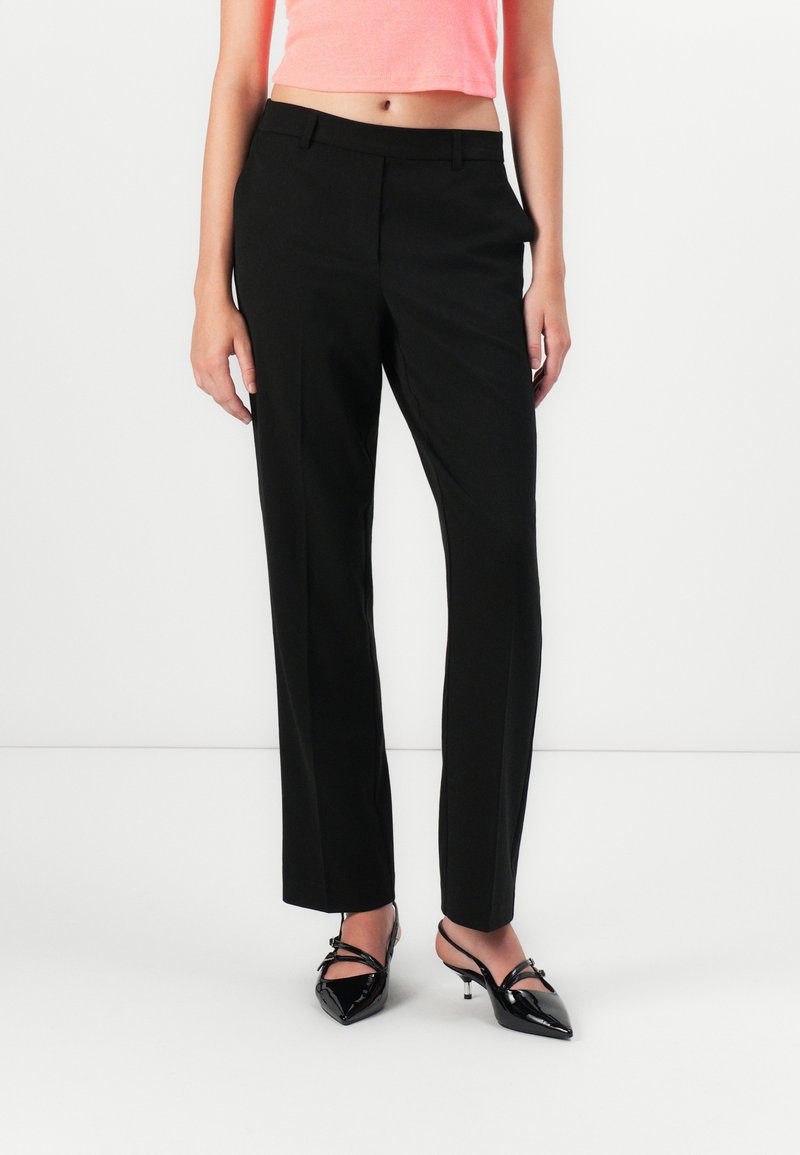Pantalons noirs ajustés avec une jambe droite, fabriqués dans un tissu lisse, disposant de poches avant et d'une taille mi-haute.