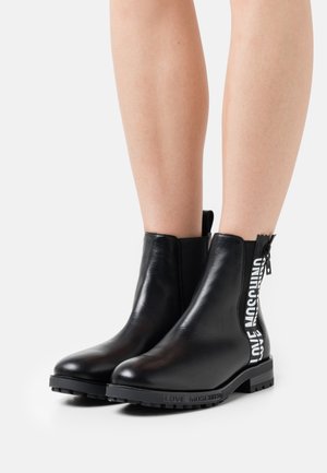 Stivaletti alla caviglia in pelle nera con cerniera laterale e dettaglio logo "LOVE MOSCHINO" bianco a contrasto. Suola in gomma e texture liscia.