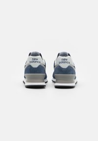 Dunkelblaue Sneaker aus Wildleder und Mesh-Materialien, mit weißen Akzenten und "New Balance"-Branding an der Ferse. Niedriges Profil-Design.