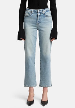 Jean en denim bleu clair avec une taille haute, coupe droite et ourlet brut. Associé à un haut noir à manches longues côtelé et des talons aiguilles noirs.
