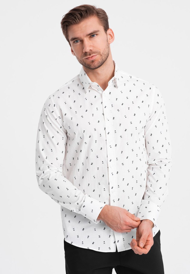 Camisa blanca de botones con patrones abstractos en negro, mangas largas y cuello estándar. La tela parece ligera con una textura suave.
