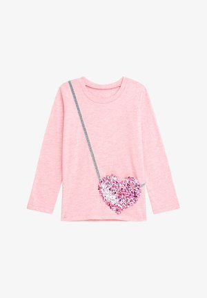 Chemise rose clair à manches longues avec une sangle diagonale argentée et un motif graphique de sac en forme de cœur pailleté rose, blanc et noir.