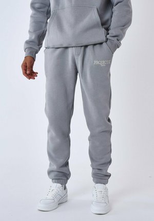 Pantaloni grigi in felpa realizzati in morbido tessuto, con vita elastica, polsini alle caviglie e logo ricamato "PROJECT X" sul davanti.