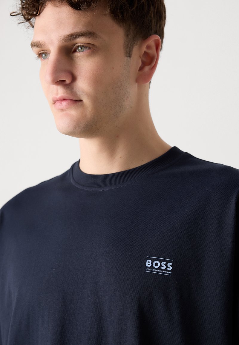 T-shirt in cotone blu scuro con collo rotondo, maniche corte e un piccolo etichetta bianca con il logo "BOSS" sul lato sinistro del petto.