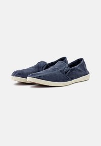 Mornarski slip-on čevlji, izdelani iz mehkega blaga, z nizkim profilom, zaobljenim prstom in teksturiranim gumijastim podplatom svetle smetane barve.