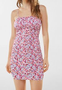 Vestido mini floral con tirantes finos, que presenta una base rosa y patrones de flores coloridos. El material es suave y ligeramente fruncido para darle textura.