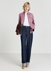 Camicia a quadri rosa e bianca, t-shirt bianca, jeans svasati blu scuro con orli risvoltati e tacchi color marrone chiaro. Design semplice e vestibilità su misura.