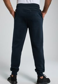 Navy Jogginghosen aus weichem Material, mit einem elastischen Bund, engen Bündchen und einer Gesäßtasche mit dezentem Branding.