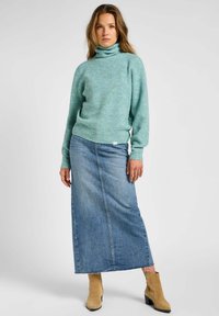 Maglione a collo alto turchese con texture a coste, abbinato a una lunga gonna di jeans e stivaletti beige. Design semplice e stile casual.