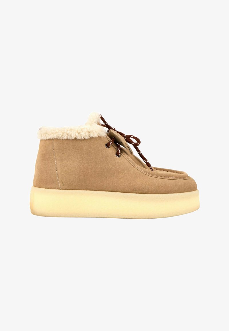 Bottines en daim beige avec semelle épaisse couleur crème, lacets marron et doublure douce en polaire blanche autour du col.