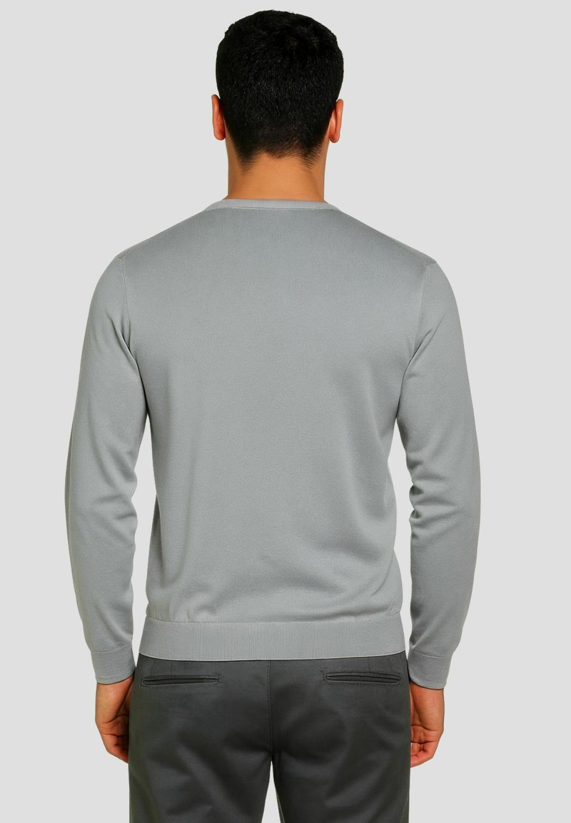 Maglione grigio a maniche lunghe, trama lavorata a maglia, scollatura rotonda e polsini a coste. Abbinato a pantaloni grigio scuro con due tasche posteriori.