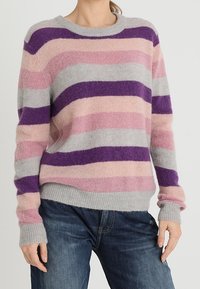 Sweter o dzianinowym splocie w szaro-różowo-fioletowe paski. Posiada okrągły dekolt i prążkowane mankiety, a także miękkie, teksturowane wykończenie.