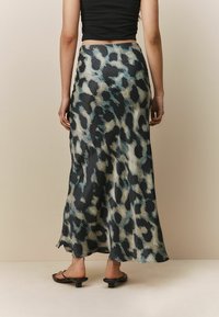 Long, flowing skirt in a leopard print design featuring shades of black, teal, and cream. Made from lightweight fabric, it has a smooth texture.