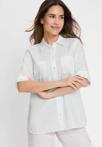 Weißes Leinenhemd mit einem Button-Down-Kragen, kurzen umgeschlagenen Ärmeln und zwei Brusttaschen; glatte Textur mit entspannter Passform.
