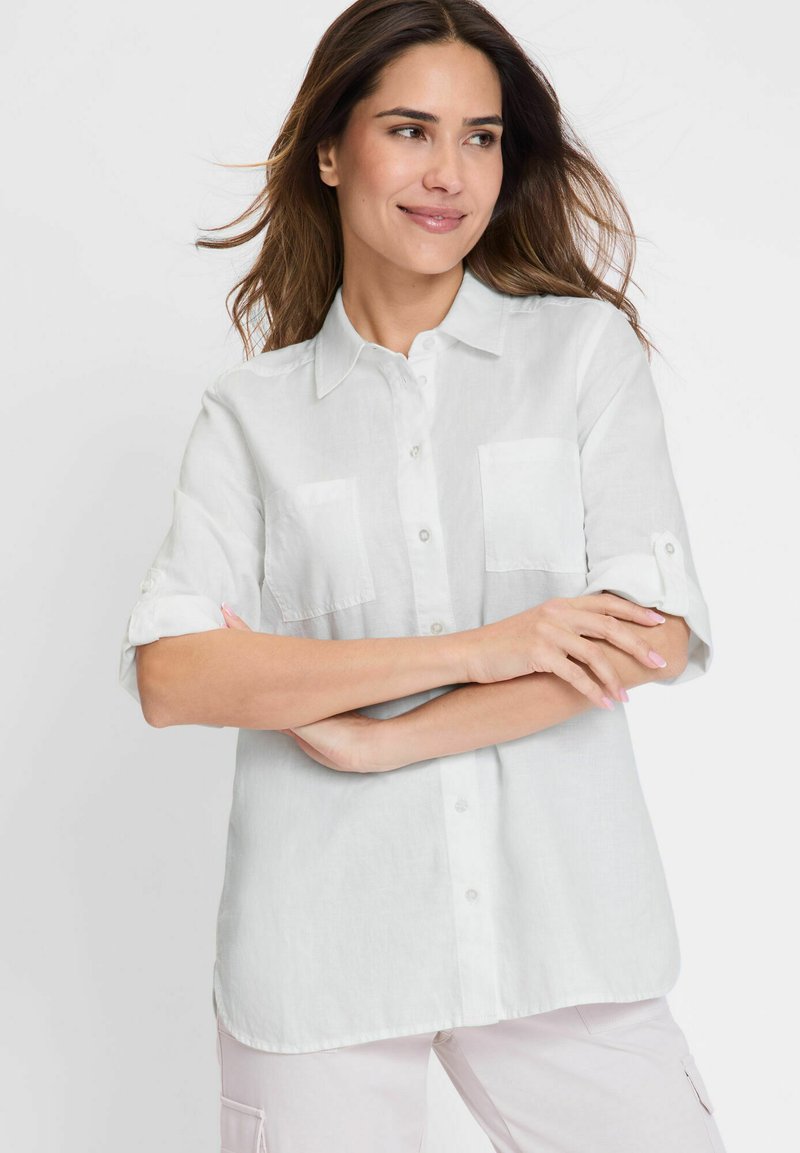 Weißes Leinenhemd mit einem Button-Down-Kragen, kurzen umgeschlagenen Ärmeln und zwei Brusttaschen; glatte Textur mit entspannter Passform.