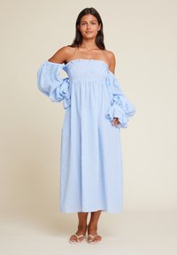 Blå og hvit gingham off-shoulder kjole med puffete ermer, lagdelt skjørt og smocket liv; ankellang og lett stoff.