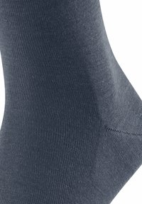 Gros plan sur une chaussette en tricot gris foncé, mettant en avant un tissu texturé avec une finition lisse et une zone de talon renforcée.