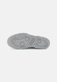 Semelle en caoutchouc gris avec un motif nervuré, des bords arrondis et des accents de grip circulaires. Logo "PUMA" embossé près du talon.