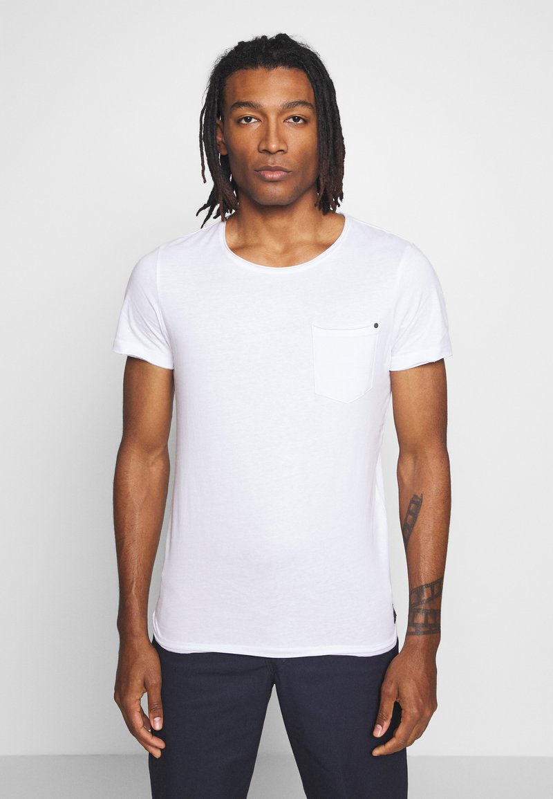 Hvid bomulds T-shirt med korte ærmer, rund halsudskæring og en venstre brystlomme med en sort accentprik. Slim fit design.