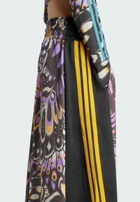Multicolored sportswear featuring a slitted design, black fabric with vibrant butterfly patterns, and yellow striped accents on the side.