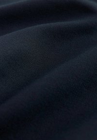 Donker marineblauwe stof met een zachte, gladde textuur, die subtiele weefsels en een lichte val toont in een close-up afbeelding.