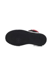 Zwarte rubberen zool met een textuurpatroon voor grip, voorzien van een opvallend rond embleem. Het ontwerp toont een stevige en platte profiel.