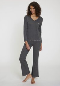 Grijs pyjama set gemaakt van zachte stof, met een V-hals lange mouw top met een scalloped zoom en bijpassende broek met vergelijkbare scalloped accenten.