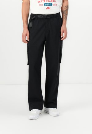 Black cargo pants with a relaxed fit, featuring side pockets, a textured belt, and a smooth, lightweight fabric. Worn with white sneakers.