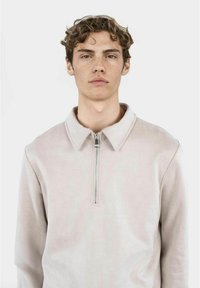 Ljusgrå zip-up sweatshirt med krage, tillverkad av mjukt tyg, med en silverdragkedja och en minimalistisk design utan mönster.