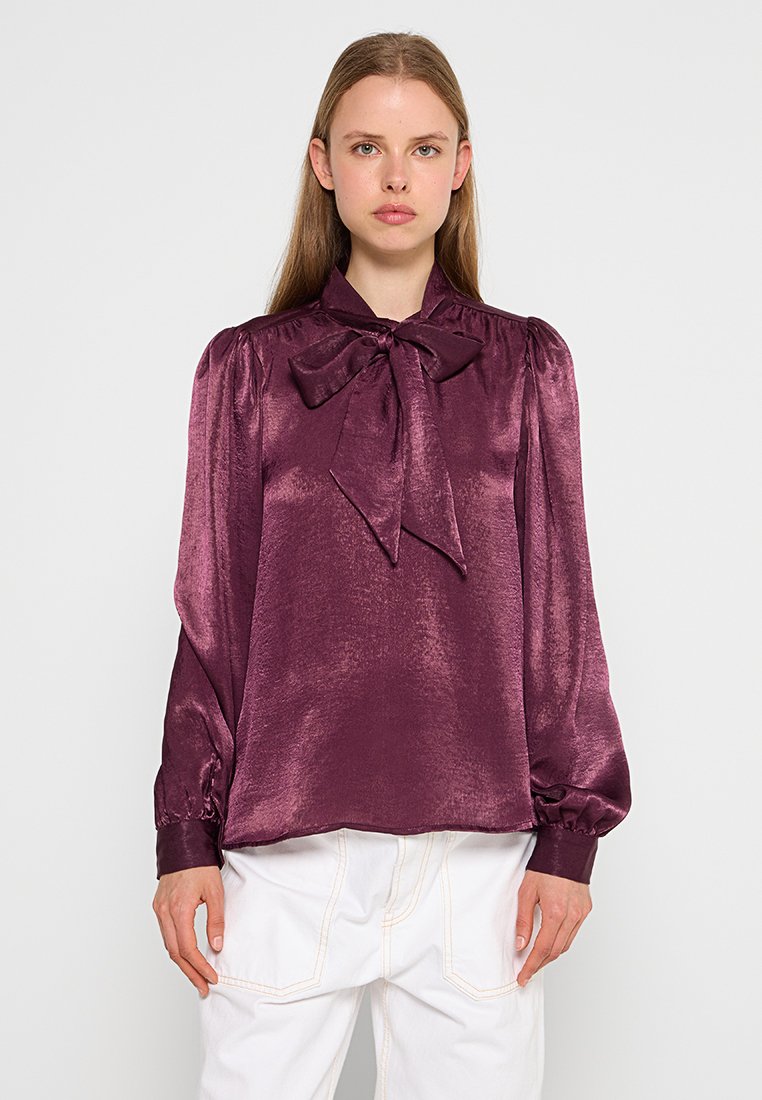 Diep paarse satijnen blouse met een strik-kraag, gepofte lange mouwen en aansluitende manchetten. Soepele textuur, licht glanzende afwerking en ontspannen pasvorm.