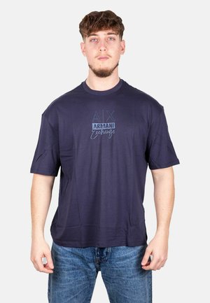 T-shirt blu navy a maniche corte con colletto girocollo e logo grafico in testo blu sulla parte anteriore. Materiale in cotone morbido; vestibilità rilassata.
