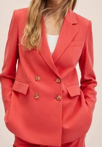 Korallenfarbener, doppelt geknöpfter Blazer mit Revers, zwei frontalen Taschen und Holzknöpfen, aus glattem Stoff mit taillierter Passform.