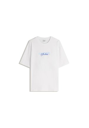 Tricou alb din bumbac cu o croială relaxată, având un text grafic de culoare albastră deschisă care spune "Valoare" în scris cursiv pe piept.