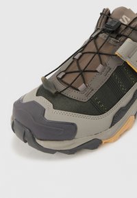 Pantofii sport gri și negri, cu o suprafață texturată, panouri din plasă și șireturi elastice; dispun de o talpă din cauciuc cu un accent galben.