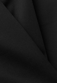 Tissu en coton noir avec une texture fine côtelée, présentant deux sections superposées qui révèlent sa couleur uniforme et la qualité du matériau.