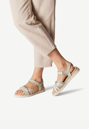 Sandale gris clair avec plusieurs brides entrecroisées et un accent argenté, dotée d'une semelle rembourrée et d'un design à bout ouvert.