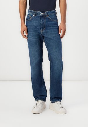 Jean en denim bleu à coupe droite, doté de cinq poches, avec des accents de couture en cuivre et une fermeture à bouton et à glissière classique.