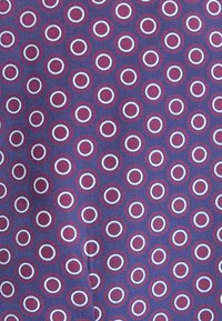 Tessuto decorato con uno sfondo blu e cerchi rossi e bianchi disposti uniformemente. Il materiale sembra avere una texture con una finitura intrecciata.