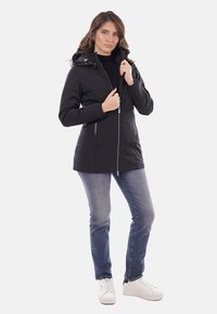 Giacca nera con zip e cappuccio, con tasche laterali e design aderente. Realizzata in materiale liscio e resistente all'acqua.