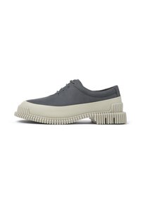 Zapatilla gris con una suela gruesa de color crema texturizada, que cuenta con un upper suave y cinco ojales para los cordones en el lateral.