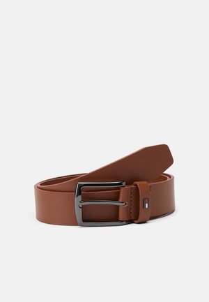 Ceinture en cuir marron avec une boucle rectangulaire argentée et un petit logo rectangulaire rouge, blanc et bleu sur la boucle de ceinture.