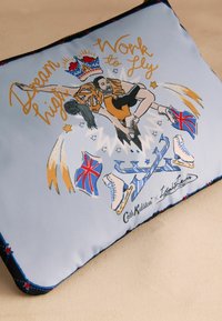 Sinine padja, millel on trükitud kujutis jäätantsust. Aktsentideks on kuldne tekst, Briti lipud ja kroonimotiiv servades.