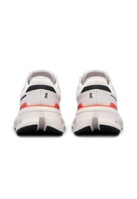 Sportschoenen in lichtgrijs met oranje en zwarte accenten, voorzien van een gestructureerd bovenwerk, een gevoerde zool en een uniek segmentontwerp van de loopzool.