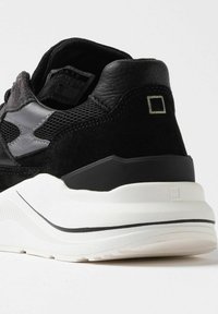 Sort sneakers med en blanding af teksturer, herunder nubuck og læder. Har en hvid mellemsål og en lille firkantet detalje på hælen.