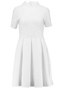 Robe blanche avec un corsage en dentelle, col montant et manches courtes, se transformant en jupe plissée en tissu lisse.