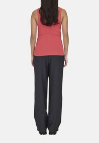 Débardeur en corail à rayures et pantalon large gris foncé ample, vus de dos. Le tissu semble doux avec un léger éclat.