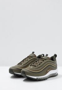 Tenisky Nike Air Max 97 v olivově zelené barvě, s vrstveným designem, síťovinou a syntetickými materiály, gumovou podrážkou a viditelnou vzduchovou jednotkou.